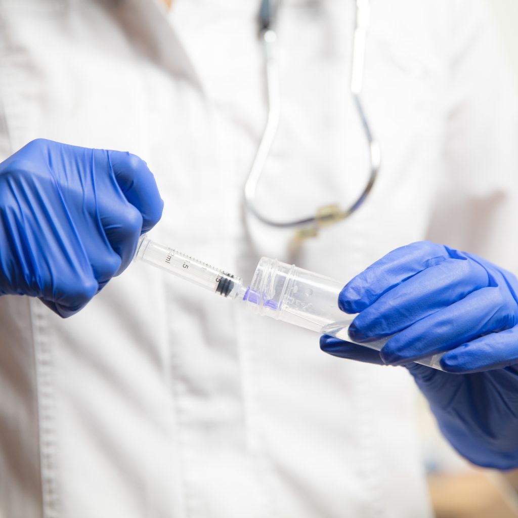 Doctor or nurse giving vaccine to patient using the syringe injected in hospital. Preparing dose in needle. Protection against coronavirus, COVID-19 pandemic and pneumonia. Healthcare, medicine.